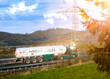 LKW mit Wasserstoff Tank fährt auf einer Autobahn durch eine Naturlandschaft. Sonnenuntergang, die Sonne scheint tief. Design auf dem LKW ist kommerziell nutzbar.