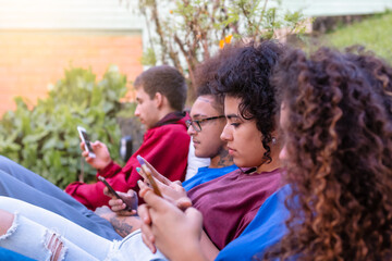 Group of multiracial friends using smartphones to sharing content on social networks. Technology lifestyle concept - Selective focus.