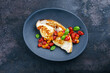 Roasted swordfish steak with tomatoes and paprika served as top view on a design plate