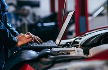 Close Up Hands Of Auto Electrician Using A Computer Laptop To Diagnosing And Checking Up On Car Engines Parts For Fixing And Repair