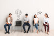 © Pixel-Shot - Young people waiting for job interview while sitting on chairs near light wall