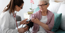 Doctor Examining Senior Woman In Nursing Home