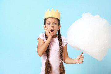 Wall Mural - Cute little girl with cotton candy on blue background