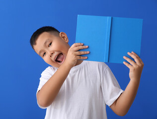 Poster - Little Asian boy with book on blue background