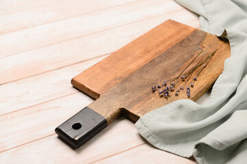 Cutting board and lavender flowers on light wooden background