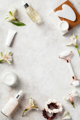 Wall Mural - flat lay composition made of natural skincare cosmetics, gua sha, face massage roller, flowers on st