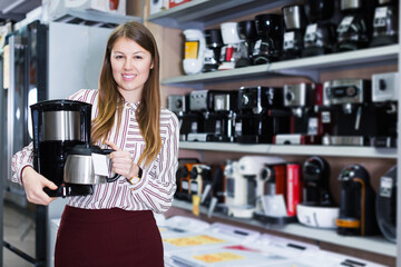 Wall Mural - Smiling seller showing coffeemaker in domestic appliances section