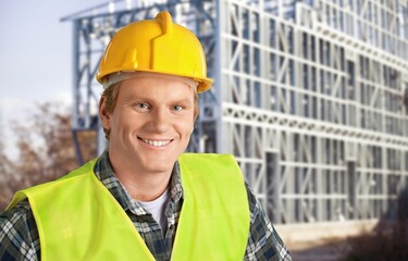 Wall Mural - Young engineer handsome man or architect with safety helmet in construction site. Standing at modern building construction.