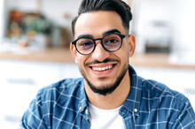 Close-up Portrait Of A Handsome Charismatic Arabian Or Indian Guy With Glasses, Freelancer Or Student, In Casual Clothes, With Perfect White Teeth, Looking At The Camera With Toothy Happy Smile