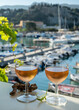 Cold rose wine in glasses served on outdoor terrace in sunlights with view on old fisherman's harbour with colourful boats in Cassis, Provence, France