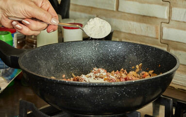 Wall Mural - Che chef pours chicken seasoning from spoon into frying pan