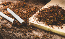 Sliced Tabaco Pile On Cutting Board And Handmade Cigarette On Wooden Table.