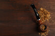 Smoking pipe with tobacco on wooden table, above view. Space for text