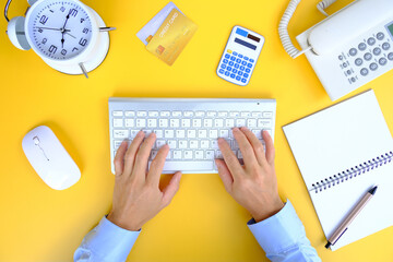 Poster - Man typing on his laptop keyboard on top of a white office desk table. Flat lay, top view with copy space.
