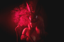 Girl In The Rabbit Mask In The Red Light Is Smoking A Cigarette In The Dark.