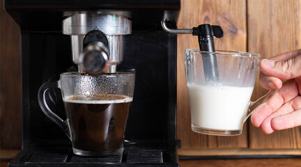 Foaming and heating milk with steam in a manual cappuccinatore machine in the kitchen. Close-up