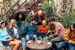 © Carlo - alternative young boys sit on the terrace of the youth hostel or student dormitory bar talking and using cell phones and laptops