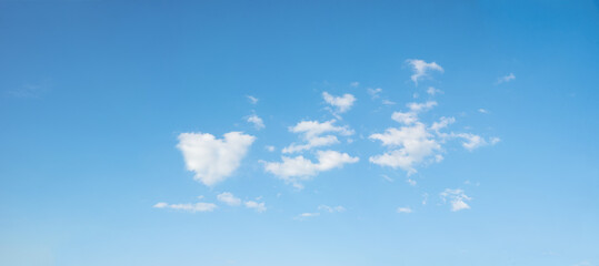 Wall Mural - blue sky background with some fluffy clouds, one in a heart shape