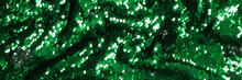 Abstract festive banner background with green sequins for holiday and party concept. Glamour shiny background with sequin texture and blinking lights. Sequins fabric of green color. Copy space