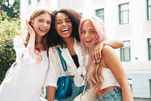 Three Young Beautiful Smiling Hipster Female In Trendy Summer Clothes.Sexy Carefree Multiracial Women Posing On The Street Background.Positive Models Having Fun