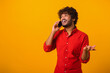 © Vadim Pastuh - Mobile communication. Portrait of man making call to consult, having pleasure talk on cellphone, discussing great news. Indoor studio shot isolated on orange background