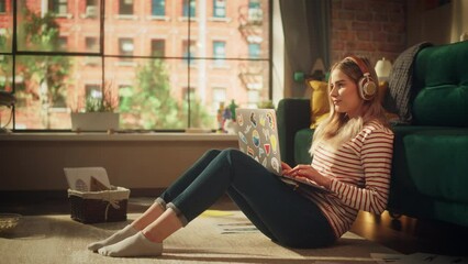 Poster - Young Girl Sitting on a Floor, Working or Studying on a Laptop. Female Freelancer Listening Music and Typing at the Keyboard. Cozy Living Room with Modern Interior with Creative Mess