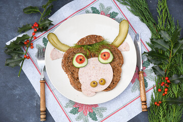 Sandwich in the form of a cheerful bull made of bread,s ausages and vegetables