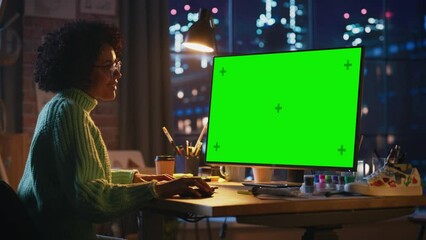Poster - Black Female Creative Employee Works on Her Personal Computer with Big Green Screen Mock Up Display in a Cool Loft Space. Positive Girl Satisfied of Results. Studying and Occupation Concept