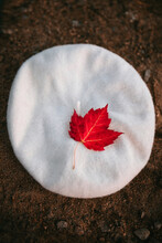 Red Leaf On White Beret Placed On Sandy Shore