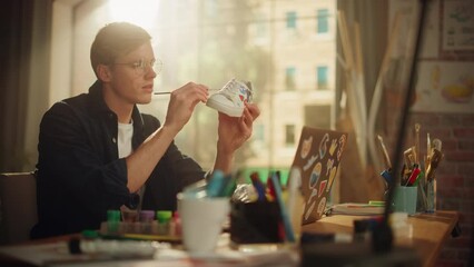 Poster - Male Teen Designer Use Paints and Brush While Draw with Inspiration at the Shoes. Millennial Artist Create Custom Made Pair of Sneakers. Next Generation and Trendy Eco Design Concept. Slow Motion