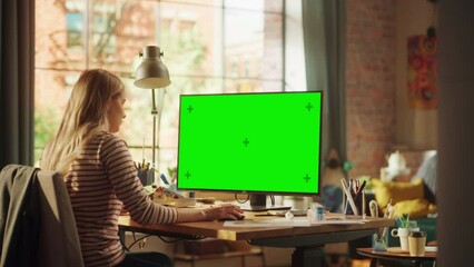 Poster - Concentrated Female Designer Working From Home at Desktop Computer with Green Screen. Woman Using Computer Mouse while Thinking About New Project. Freelance and Millennial People Concept