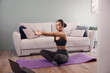© verona_studio - Woman training at home and watching videos on laptop, girl  exercising in living room