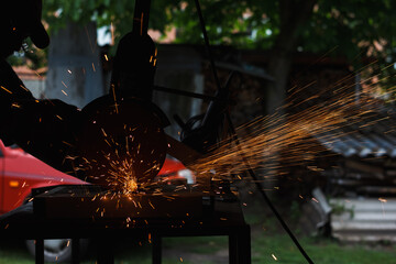 Wall Mural - The master cuts the metal with a grinding machine. Sparks from metal in the workshop (shallow DOF)