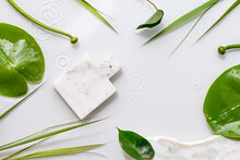 Mockup With Place For Product On Marble Board. Water Lily And Sedge Leaves On Off White Background. Natural Sunlight, Long Shadows. Flat Lay With Splashes, Rings Of Water.