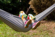 © Tomasz - Anonymous child, school age girl laying on a hammock feet legs up, face obscured, outdoors scene, summer fun and leisure, resting, boredom abstract concept, shoes closeup, vacation, holidays