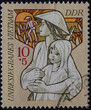 GERMANY, DDR - CIRCA 1971: a postage stamp from GERMANY, DDR, showing an armed Vietnamese woman with a child, rice farmer in front of the rising sun. Invincible Vietnam. Circa 1971
