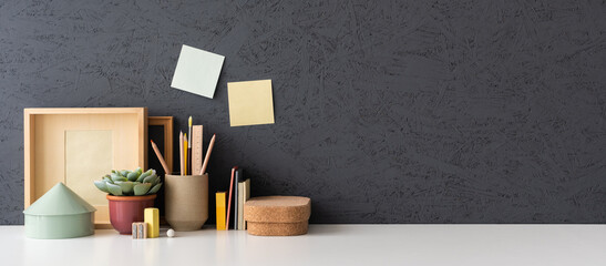 Wall Mural - Desk with notebook, desk objects, office supplies, books, and cactus on a dark background..