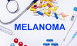 On a white background pills, stethoscope, syringe, thermometer and text MELANOMA. Medical concept