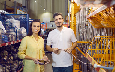 Wall Mural - Portrait of happy smiling customers at a modern DIY store. Young married couple shopping for hardware goods together. Man and woman buying good quality stainless steel hoses for their new apartment