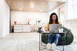 © Prostock-studio - Woman sitting at desk, using computer and writing in notebook