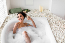 Happy Young Woman Lying In Hot Bath With Glass Of Champagne, Celebrating Holiday At Home, Free Space