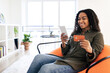 © Prostock-studio - Smiling black lady using phone and credit card at home