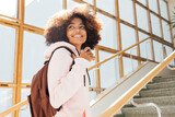 Smiling girl looking back while standing on stairs in school. Student going for the lecture.