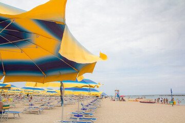 Beach umbrellas and couches on blue sky and sea background on the beach of Italy. Popular Tourist Resort at Adriatic Sea on beach of , Rimini Adriatic coast, Italy