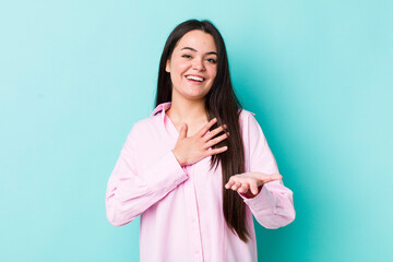 Wall Mural - young adult woman feeling happy and in love, smiling with one hand next to heart and the other stretched up front