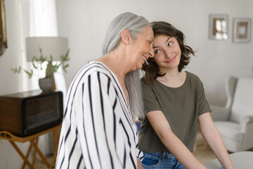 Senior grandmother with teenage granddaguhter having good time together at home.