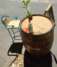 Improvised Table With A Barrel Of Wine, With A Plant And Blue Chair On One Side - Elegant Vintage Style Terrace Outside A Bar, In The Middle Of The Street