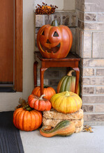 Ceramic Jack O'lantern On Table And Harvest Of Pumpkins And Squash As Autumn Decoration On Doorstep