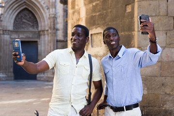 Wall Mural - African-american tourists taking selfie on mobile phone at historical street