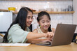 © wattana - Asian mother helping her daughter doing homework with laptop at home.